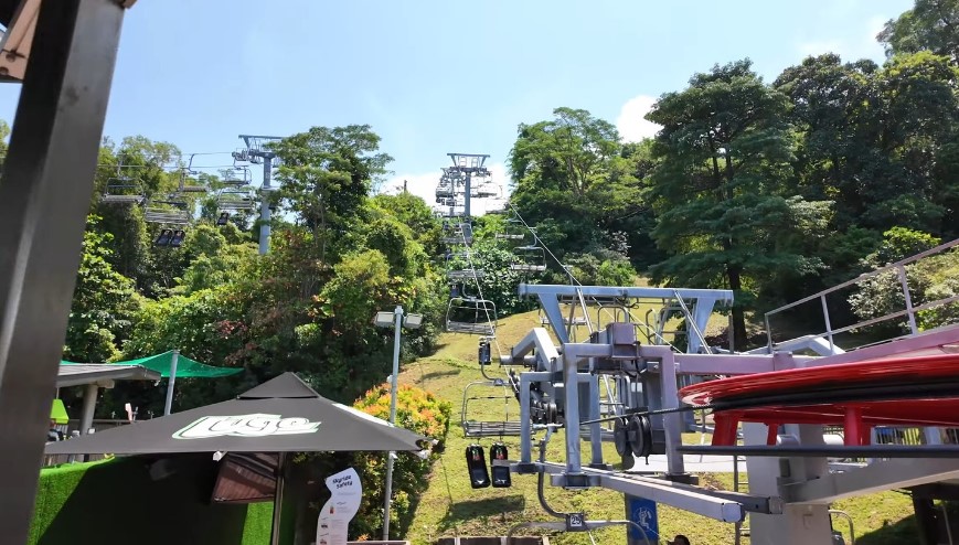 A scenic view of the chairlift, surrounded by verdant trees and a clear sky