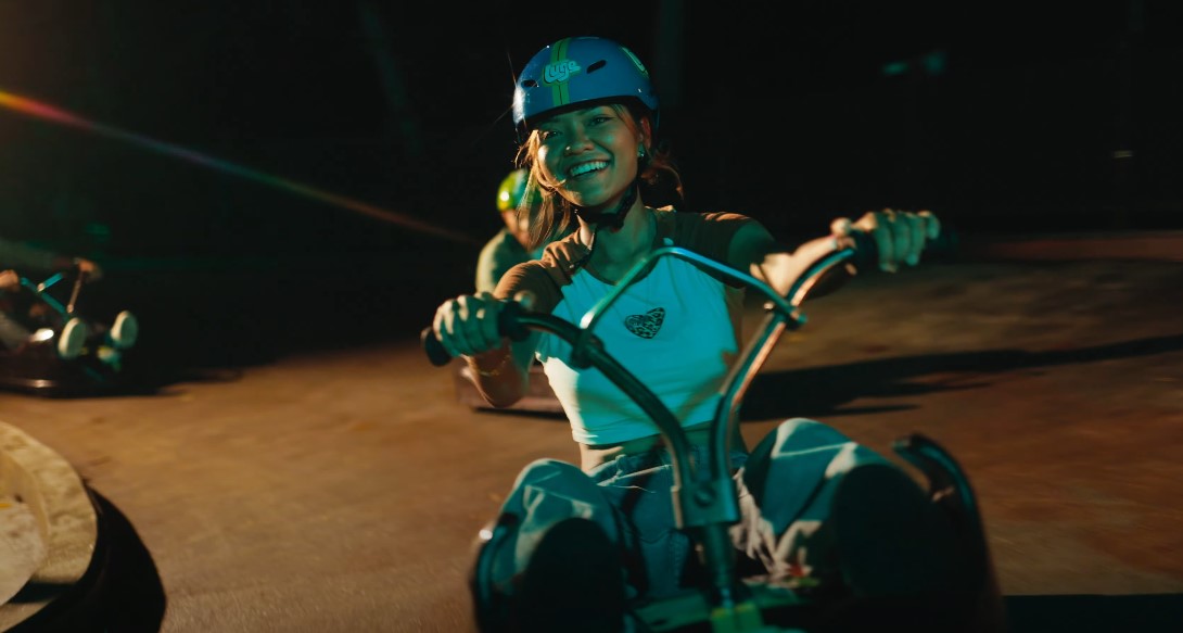 Young woman smiles brightly while operating a go-kart at night