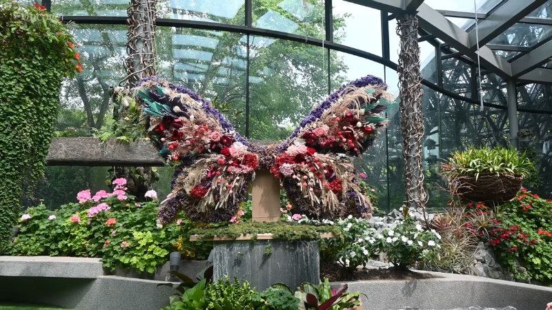 A butterfly-shaped floral sculpture surrounded by vibrant greenery inside Floral Fantasy at Gardens by the Bay