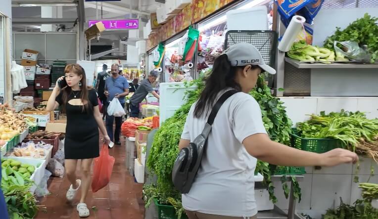 A woman in a black dress talks on her phone while navigating a bustling market