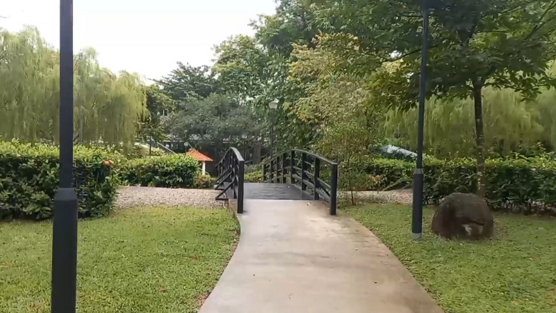 Pathway leading to a small bridge surrounded by greenery in Tiong Bahru Park