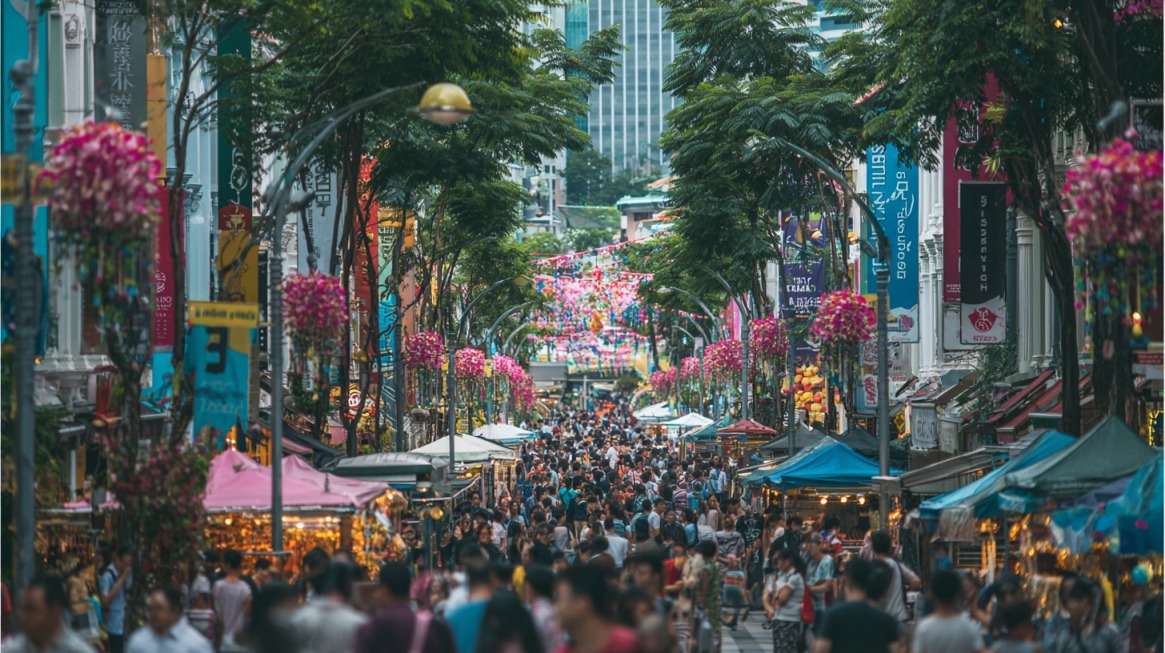 Busy Bugis Street in Singapore filled with crowds, market stalls, and colorful floral decorations hanging above the street