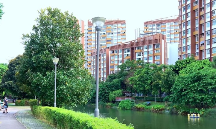 A river flows through a city park, bordered by buildings on both sides