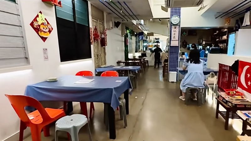 Interior of Mama Diam in Singapore with retro décor, blue tablecloths, and casual seating that recalls old-school kopitiam charm