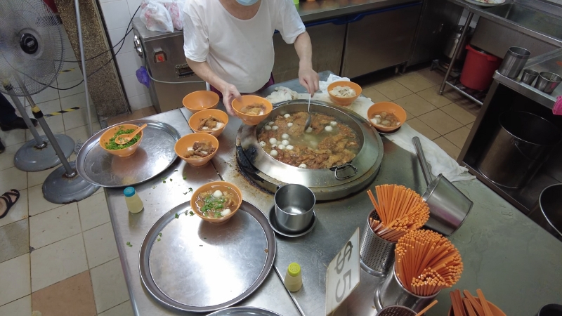 A vendor serves fresh fishball noodles made with morning-caught fish at a Singapore wet market