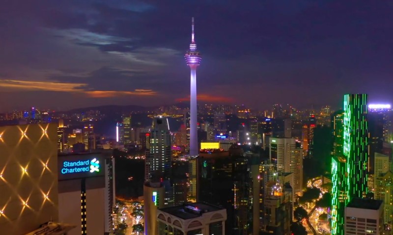 Skyline of Kuala Lumpur at dusk, featuring the illuminated KL Tower and vibrant city lights